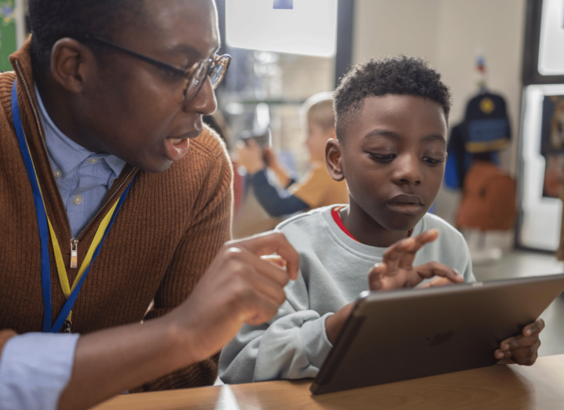 Teacher helps a primary school student with their work on iPad