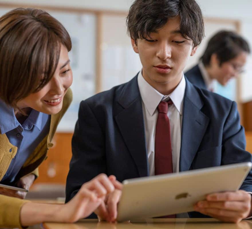 A student showing a teacher the work they have done on their iPad device.